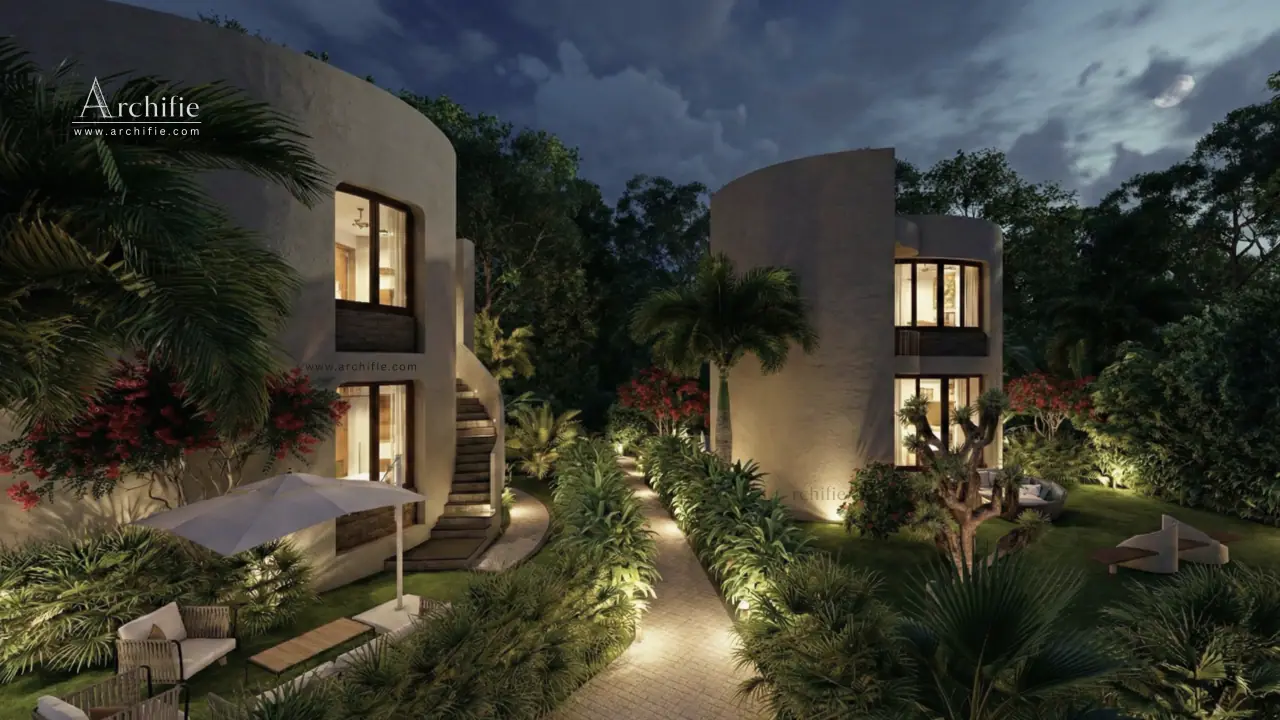 Two curved villas lit from within at dusk, a lamplit path running between them